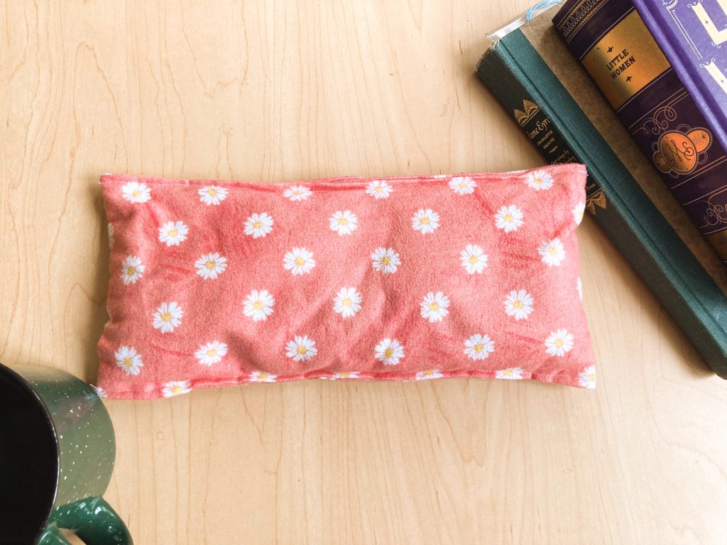 pink heat pad with books and cup