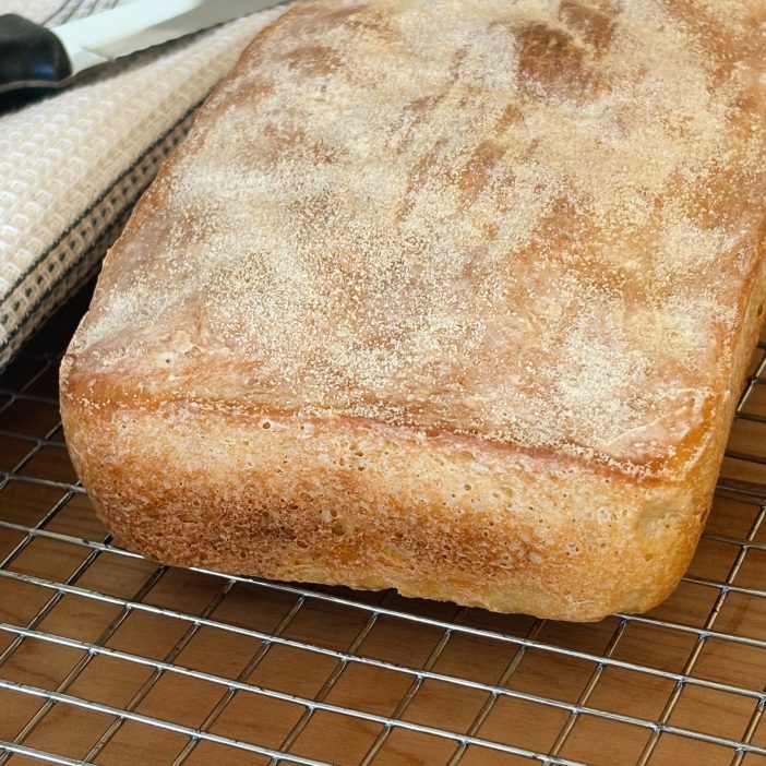 loaf of sourdough english muffin bread with towel