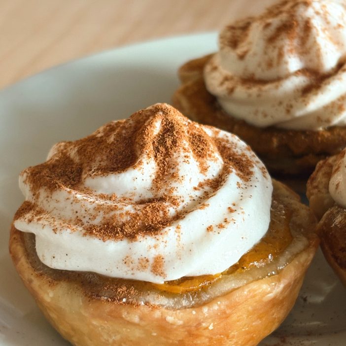 mini pumpkin pie with whipped cream on white plate