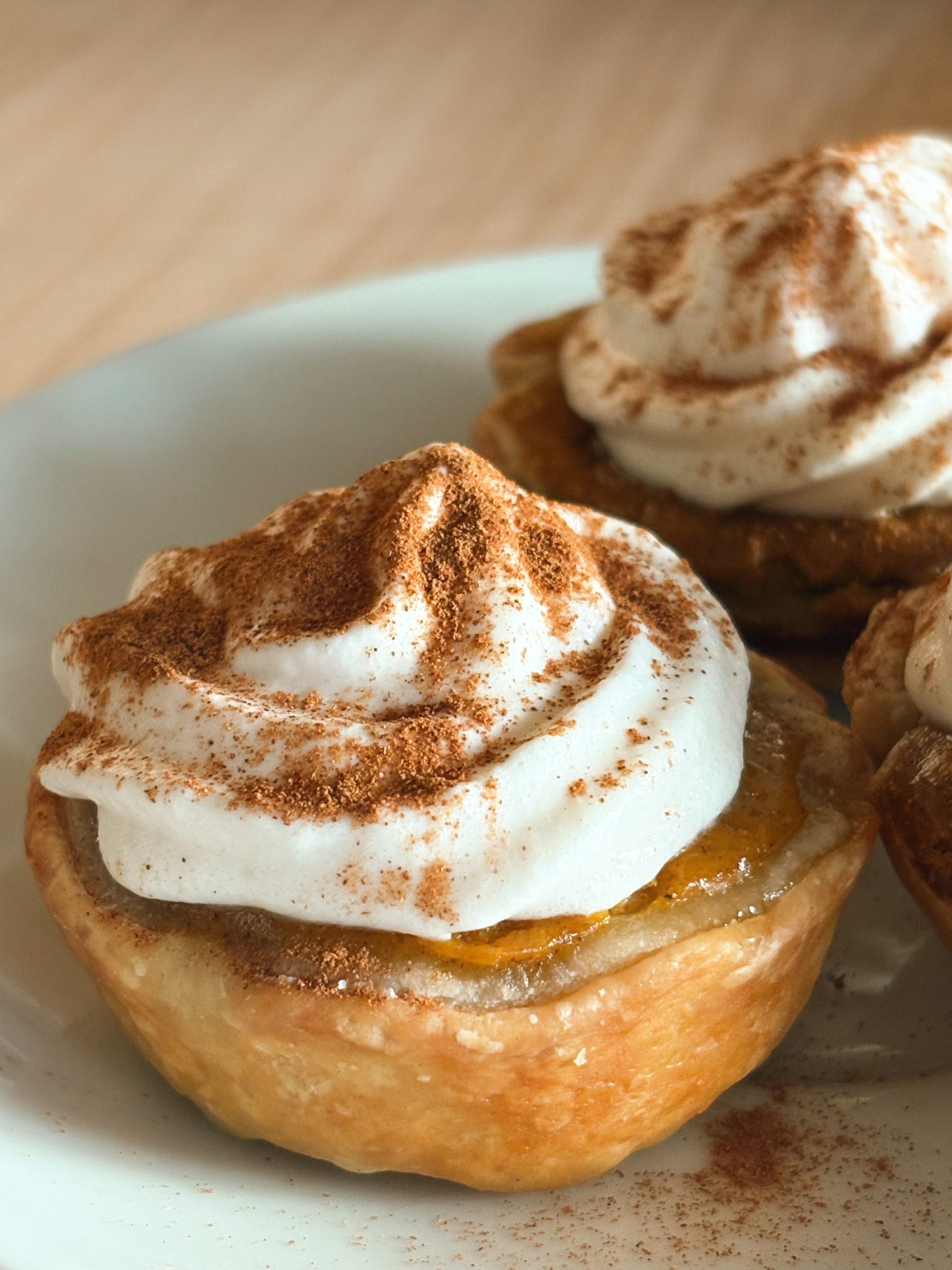 mini pumpkin pie with whipped cream on white plate
